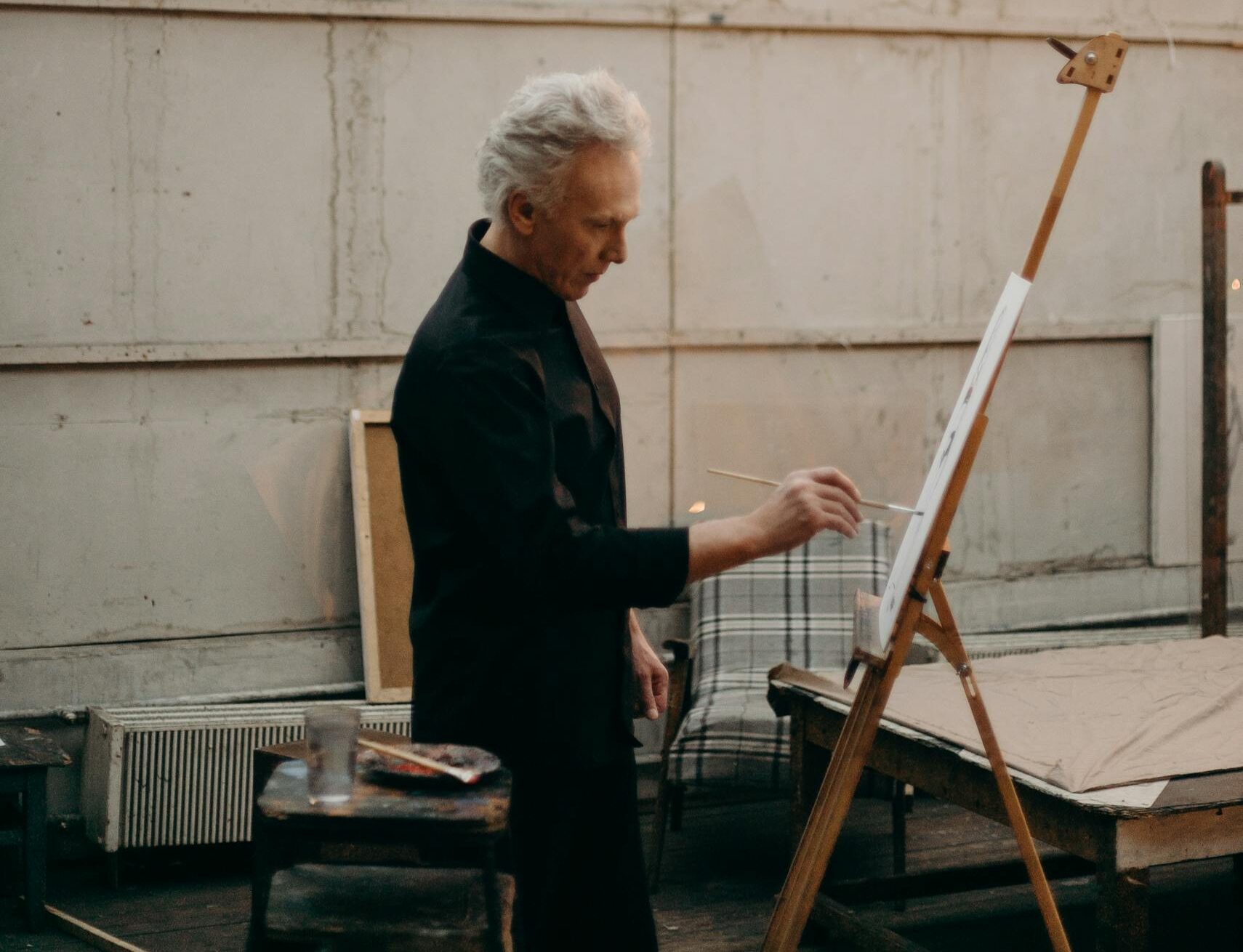 An artist deeply focused while painting on a canvas in a well-lit studio.
